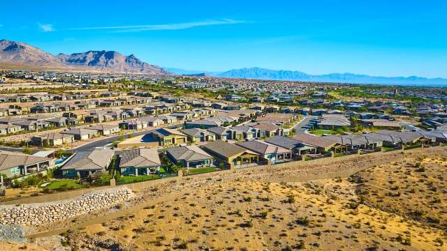 Aerial view of suburban homes nestled against mountains under a clear blue sky.