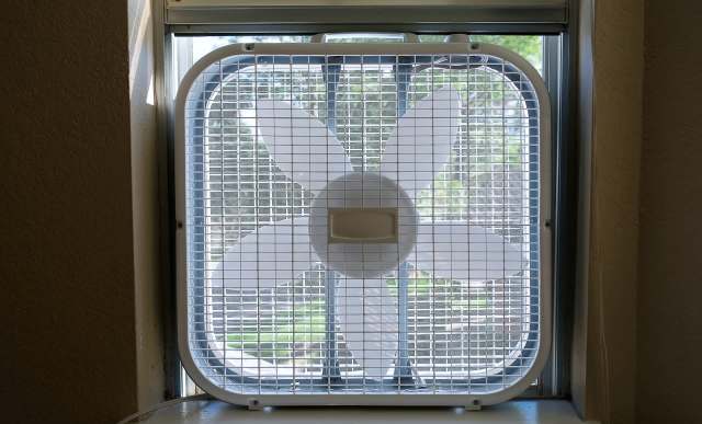 A window fan with a flower-shaped design installed in a dimly lit room.