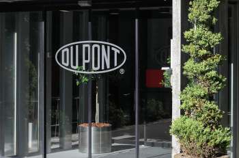 A glass entrance featuring the DuPont logo and a neatly trimmed green plant in a planter.