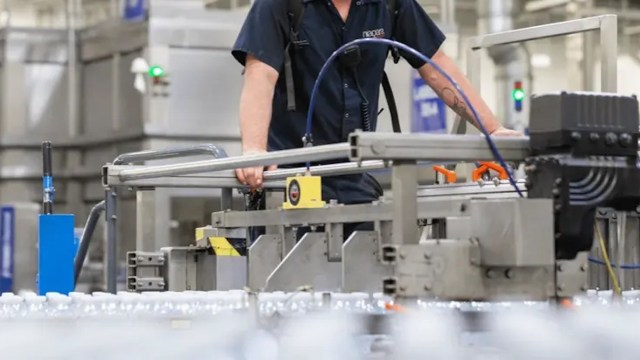 A worker operating machinery in a beverage production facility.