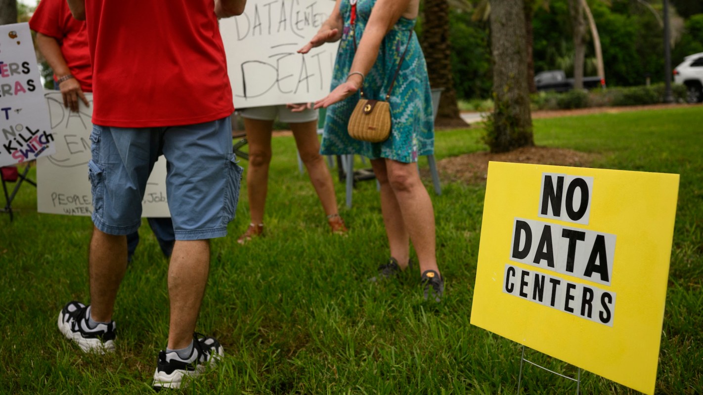 Protesters holding signs opposing data centers.