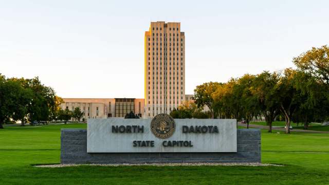 The North Dakota State Capitol building with a sign in front indicating its name.