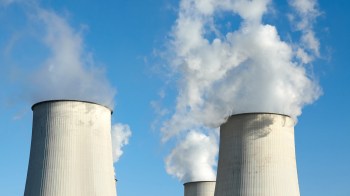 Cooling towers releasing steam against a clear blue sky.