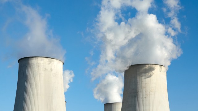 Cooling towers releasing steam against a clear blue sky.