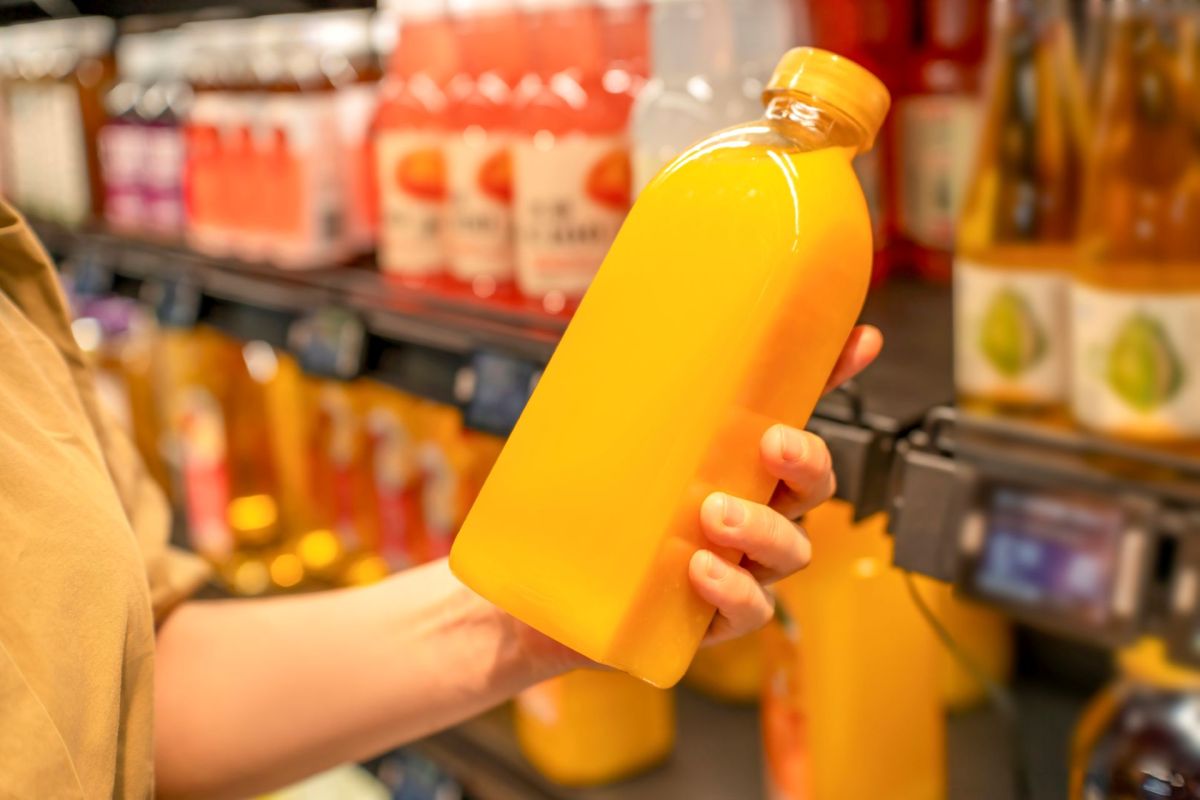 A shopper holding a bottle of orange juice.