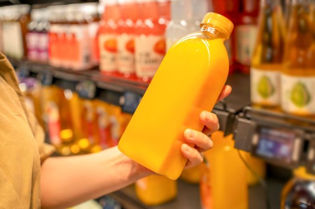 A shopper holding a bottle of orange juice.