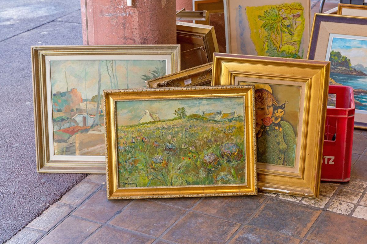 Framed paintings displayed on a stone floor.