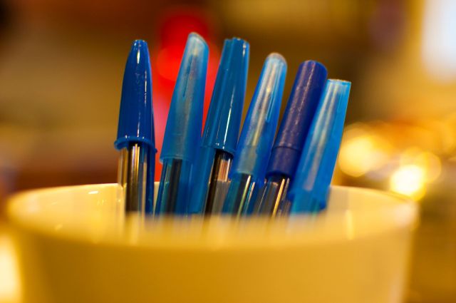 blue pens in a cup focused on the pen caps