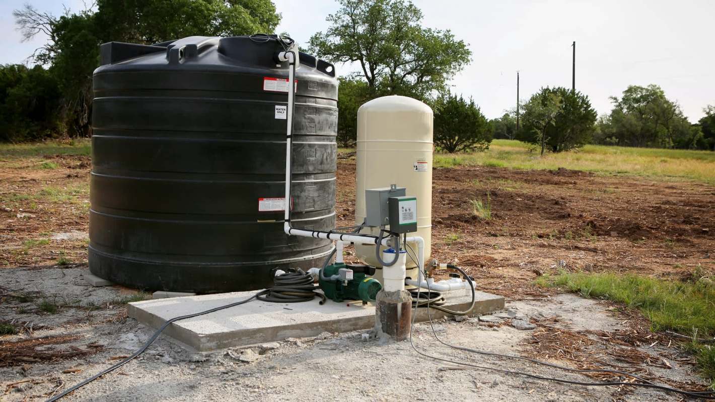 A large storage tank next to a water pump.