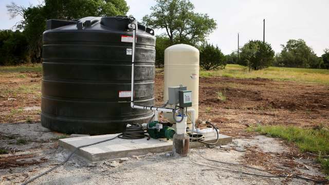 A large storage tank next to a water pump.