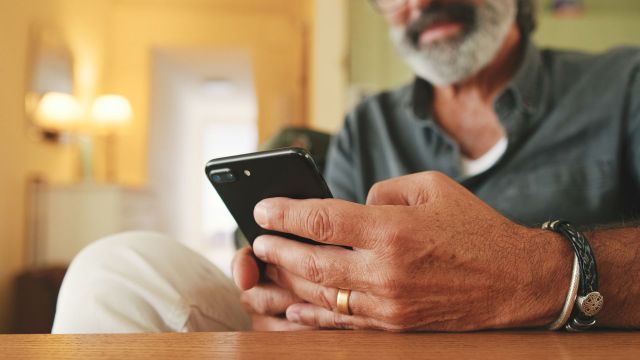 A man holding a smartphone while seated at a table.