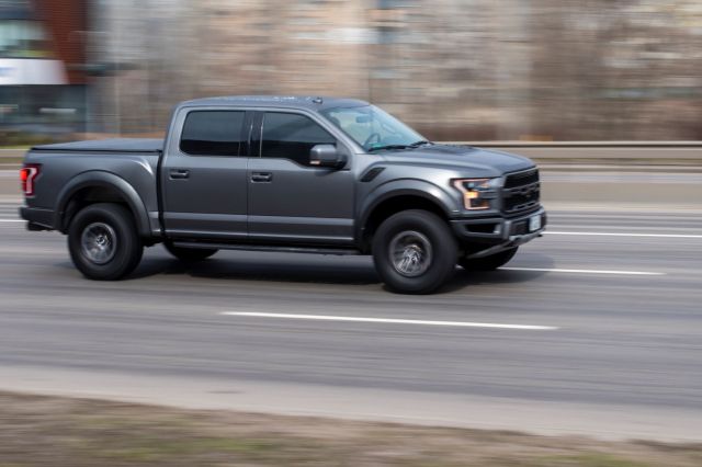 A grey pickup truck driving fast on a highway.