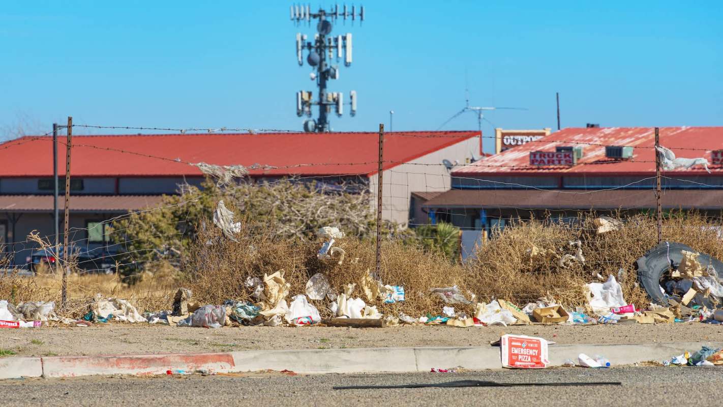 Trash piled next to a barbed wire fence.