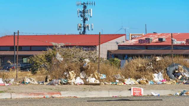 Trash piled next to a barbed wire fence.