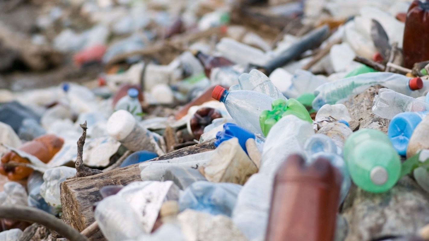A cluttered beach covered in various plastic bottles and debris.