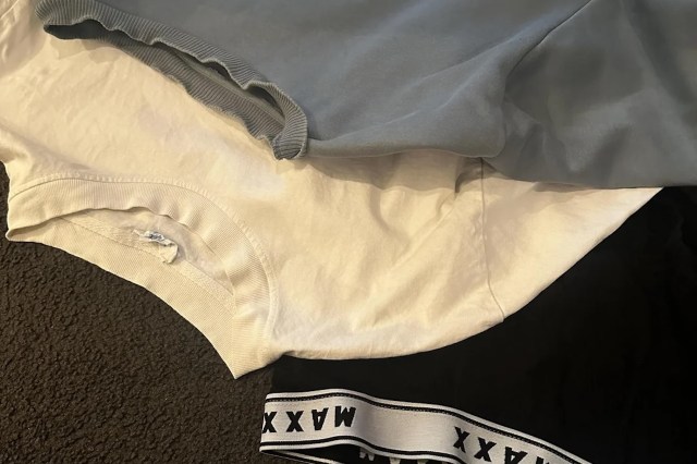 A stack of three clothing items: a gray top, a white T-shirt, and black shorts with a patterned waistband.
