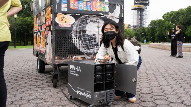 A person posing with an inverter adapter for a clean-powered food cart.