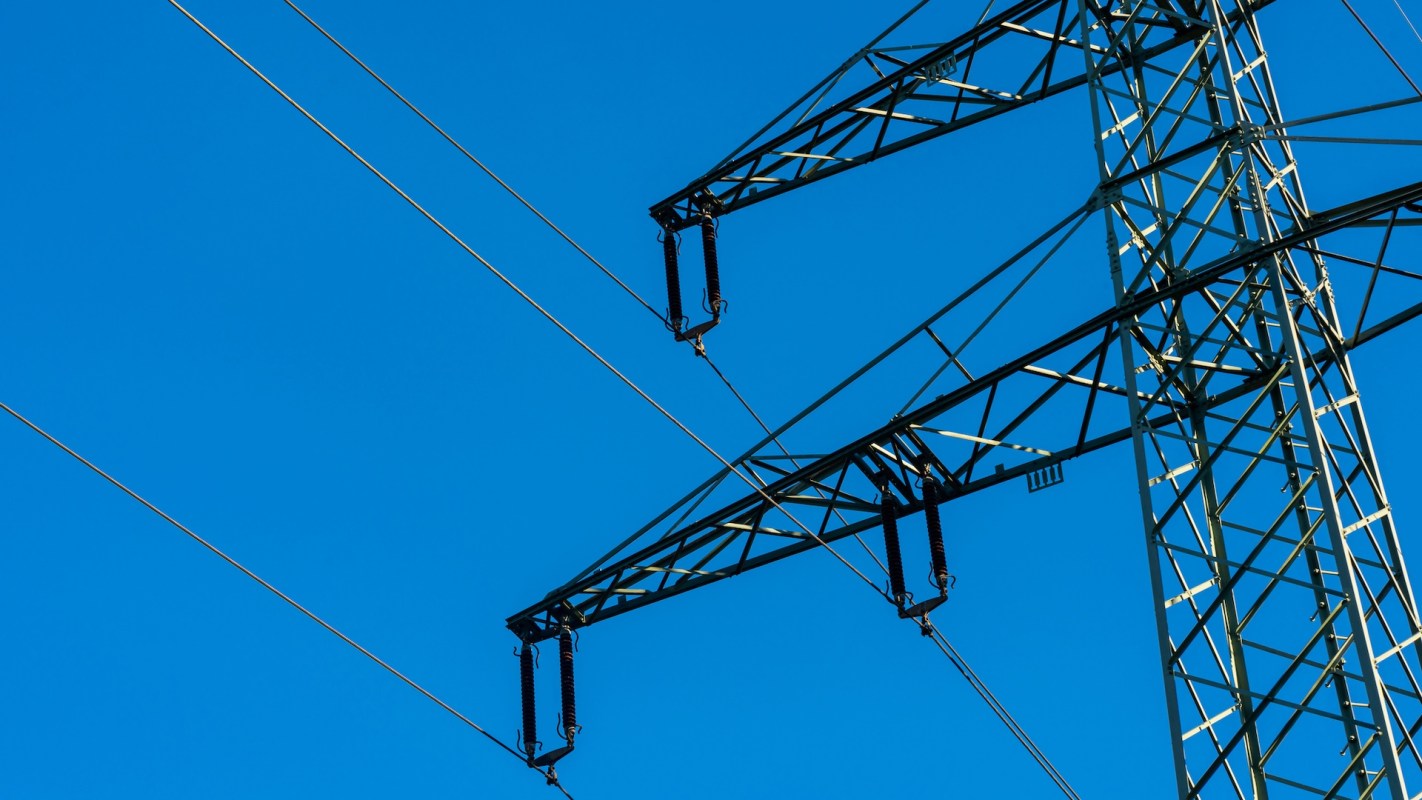 A power line tower against a clear blue sky.