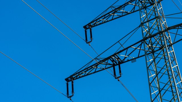 A power line tower against a clear blue sky.
