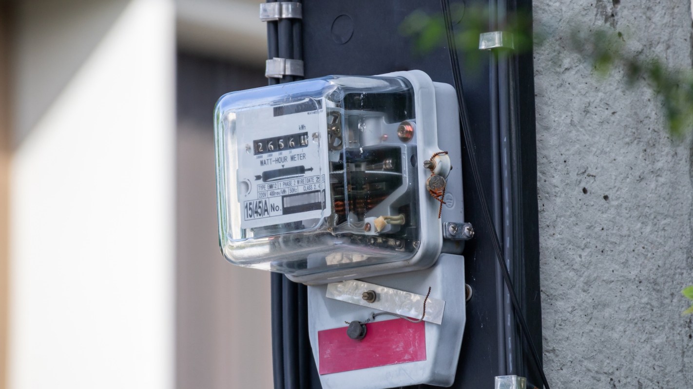An electric meter mounted on a concrete wall.