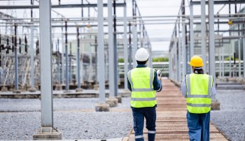 Two workers walking up to a power plant.
