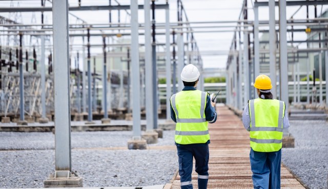 Two workers walking up to a power plant.