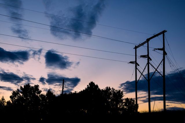 Silhouetted power lines and trees against a twilight sky.