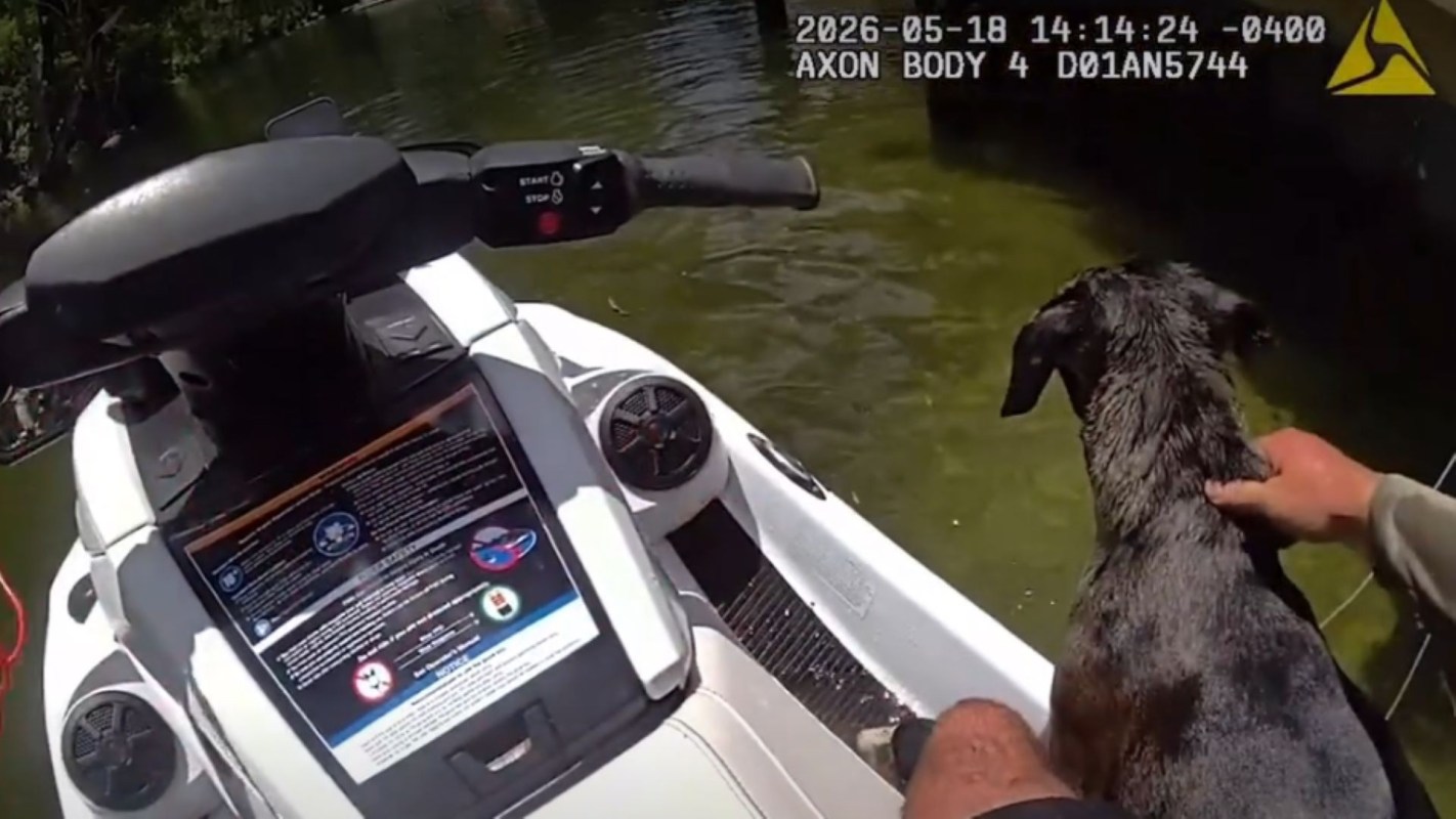 Deputy Shafer holding the dog on a jet ski.