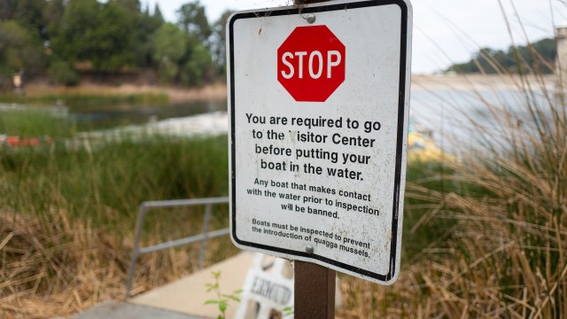 A sign with a red stop symbol, instructing boaters to visit the center before entering the water.