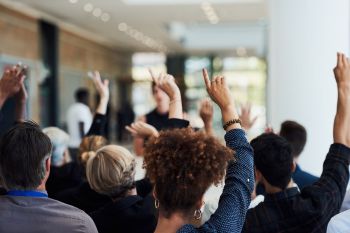 A group of people in an audience raising their hands.