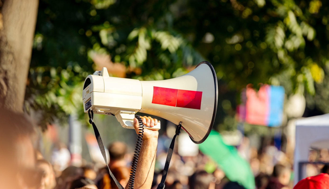 A person raising a megaphone at rally.