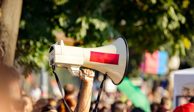 A person raising a megaphone at rally.