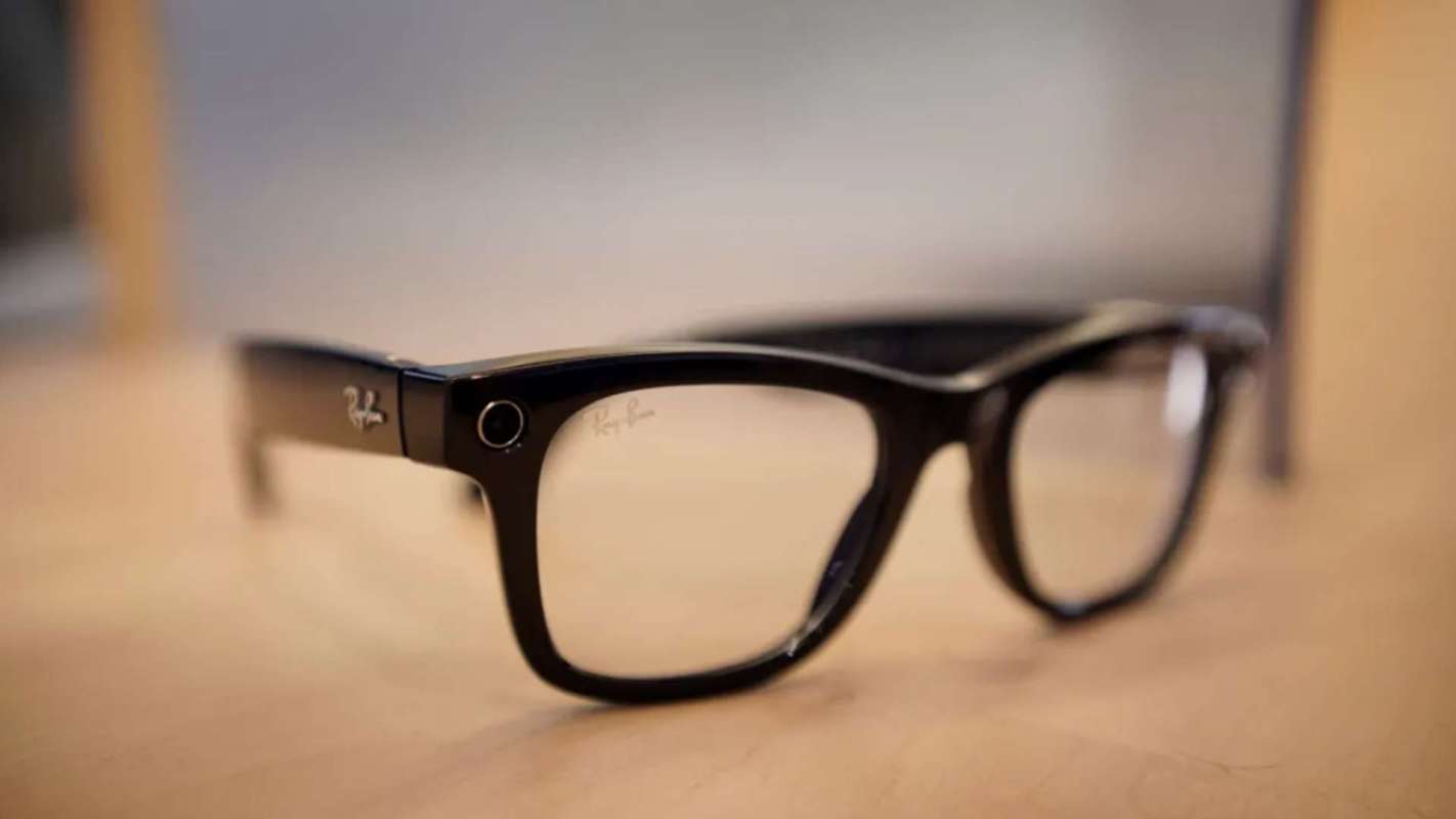 A close-up of black Ray-Ban eyeglasses resting on a wooden surface.