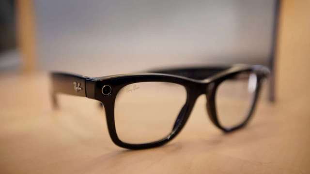A close-up of black Ray-Ban eyeglasses resting on a wooden surface.