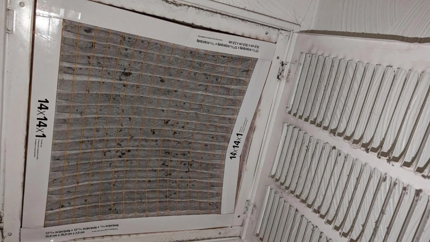 A dirty air filter with a grid pattern, mounted in a ventilation system.