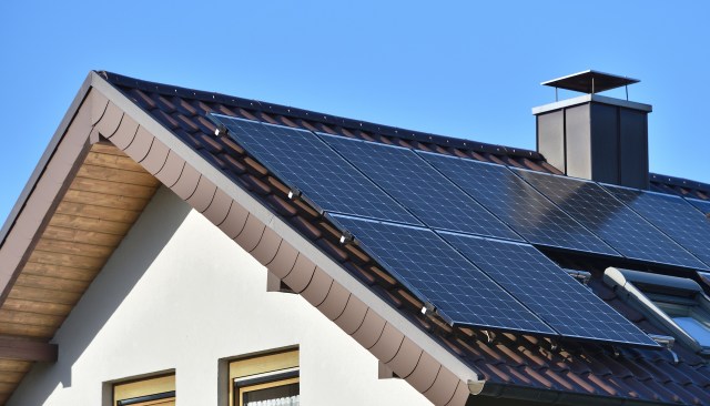 Solar panels installed on the roof of a house under a clear blue sky.