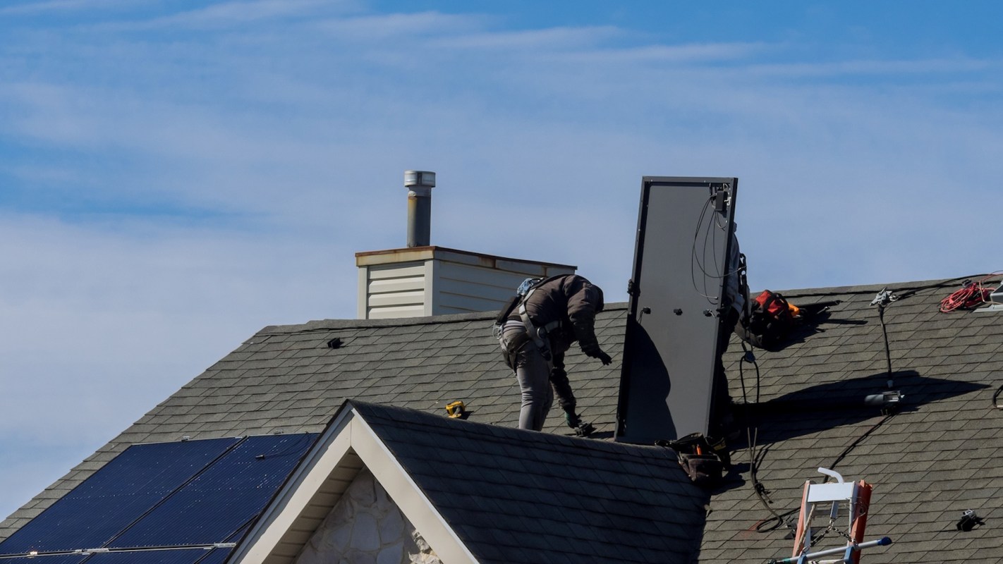 A worker installing solar equipment on a roof.
