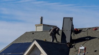 A worker installing solar equipment on a roof.