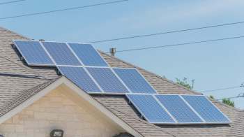 A residential roof featuring several solar panels under a clear blue sky.