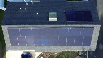 An overhead view of a house roof with solar panels.