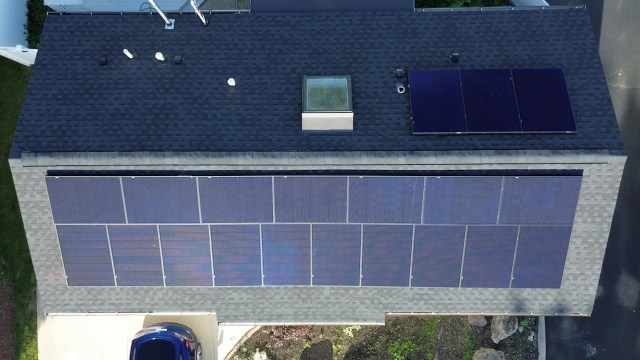 An overhead view of a house roof with solar panels.
