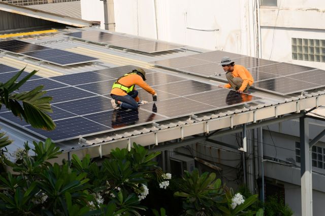 Two workers installing solar on a roof.