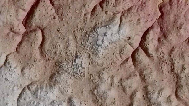 An aerial view of a rugged terrain with faint outlines of ancient structures and features in a reddish landscape.