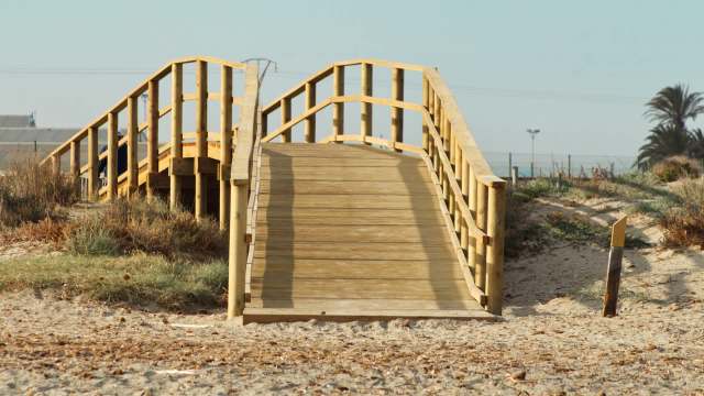 A wooden bridge leading to a sandy beach.
