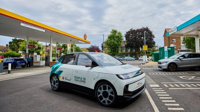 A Triple 10 Challenge electric vehicle parked at a Shell station.
