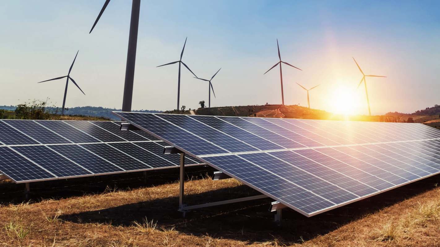 Solar panels and wind turbines at sunset.