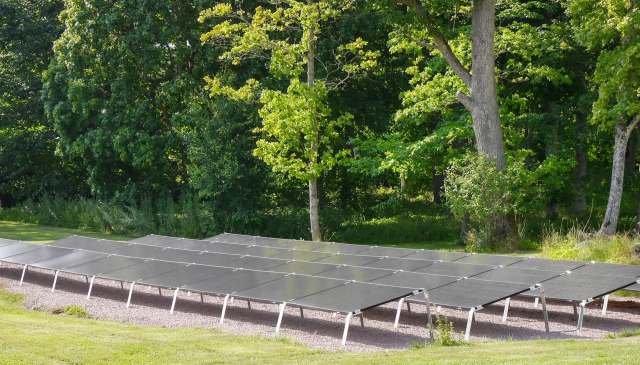 A row of solar panels on mounts over gravel.