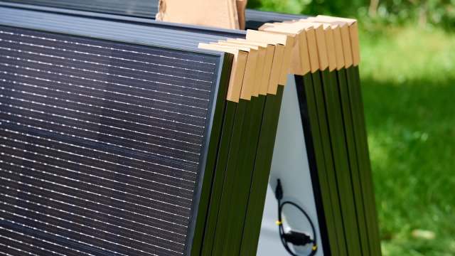 Stacked solar panels with cardboard edge protectors.