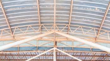A close-up view of a metal industrial roof structure featuring beams and corrugated panels.