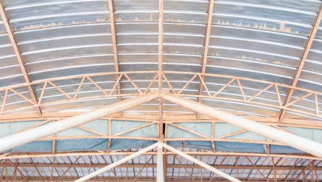 A close-up view of a metal industrial roof structure featuring beams and corrugated panels.